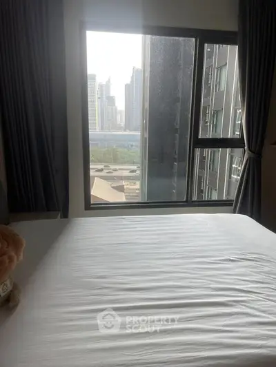 Modern bedroom with large window offering stunning cityscape view, perfect for urban living.