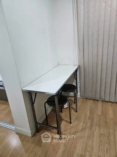 Compact study nook with sleek white desk and stools, perfect for small spaces.