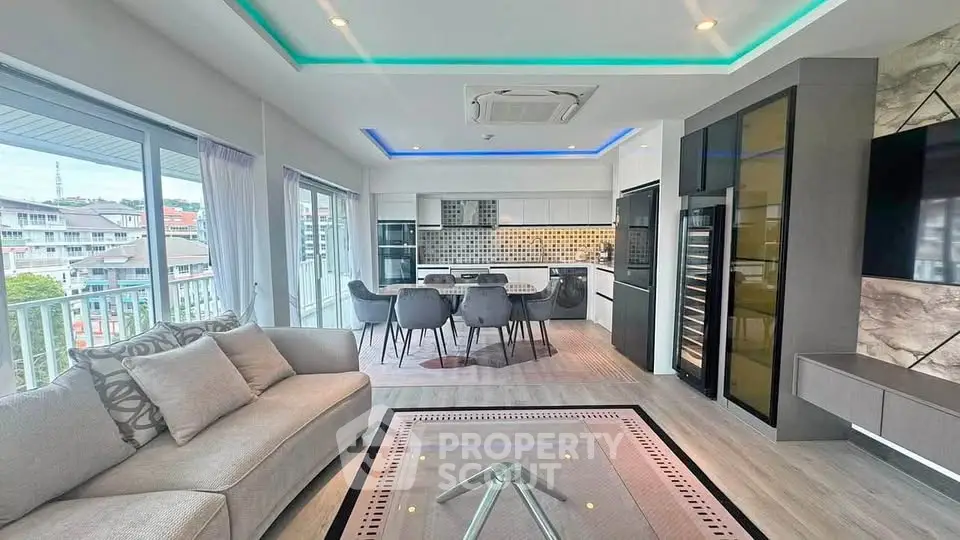 Modern open-plan living room with stylish kitchen and large windows offering city views.