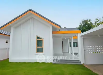 Modern white house exterior with unique window design and lush green lawn