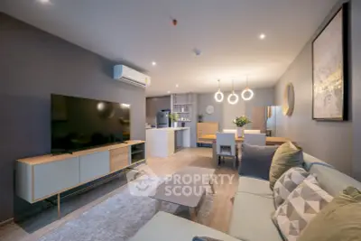 Modern living room with stylish decor and open kitchen layout, featuring a large TV and cozy seating area.