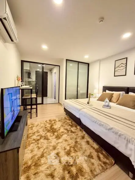 Modern bedroom with cozy decor and open layout, featuring a plush rug and stylish furnishings.
