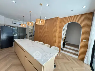 Modern kitchen with marble island, wooden accents, and stylish lighting