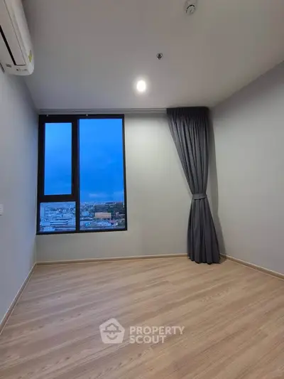 Spacious empty room with large window offering stunning city view, perfect for customization.