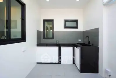Modern minimalist kitchen with sleek black and white design, featuring closed layout and stylish fixtures.