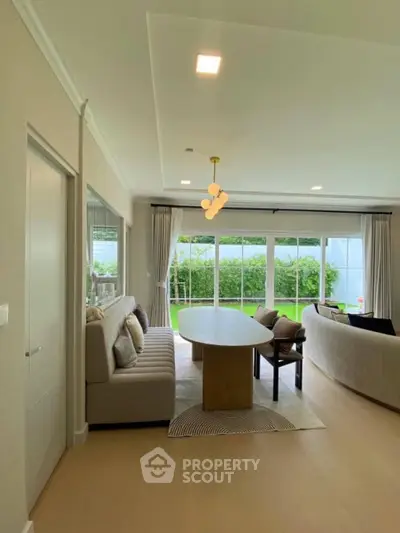 Spacious living room with modern furniture and garden view, perfect for family gatherings.