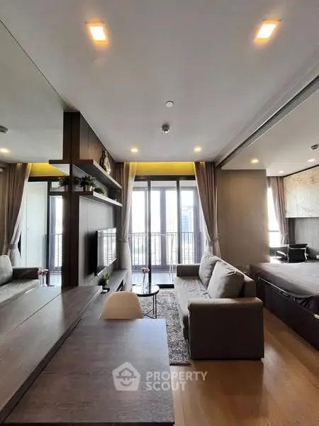 Modern living room with cozy sofa and large windows opening to balcony