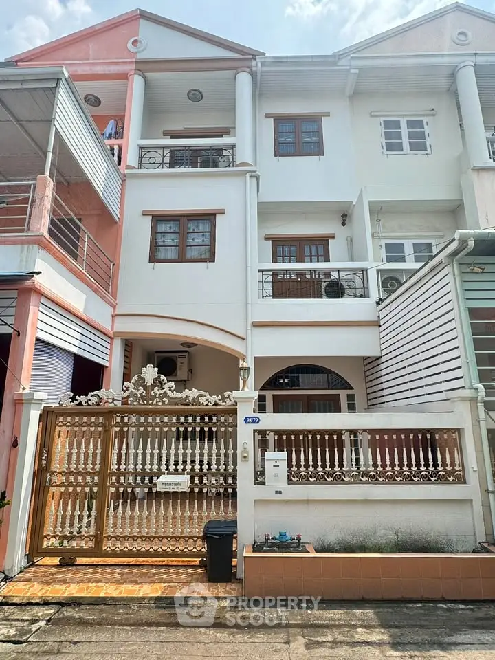 Charming three-story townhouse with ornate gate and balcony in a vibrant neighborhood.