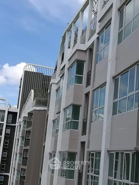 Modern apartment building exterior with large windows and unique architectural design.