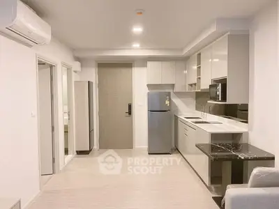 Modern open-layout kitchen with sleek cabinetry and stainless steel appliances in a bright apartment.