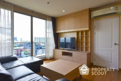 Modern living room with city view, featuring sleek furniture and abundant natural light.