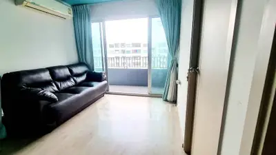 Bright living room with black leather sofa and balcony view in modern apartment.