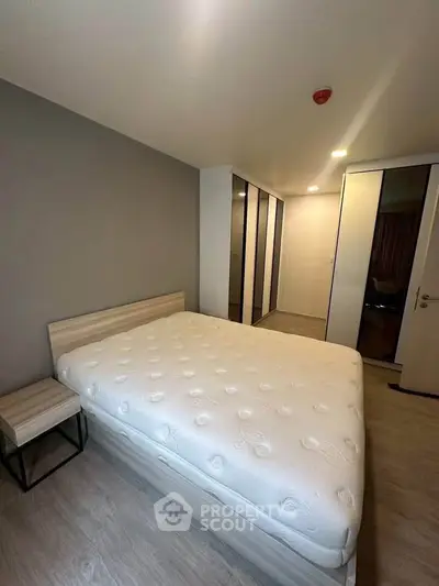 Modern bedroom with sleek design and ample closet space in a contemporary apartment.