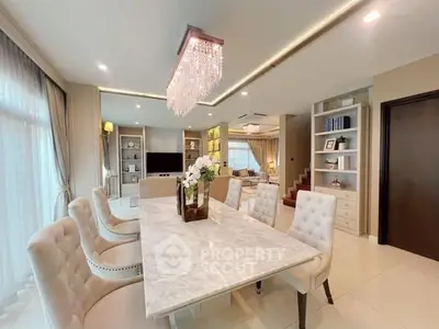 Luxurious open-plan living and dining area with elegant chandelier and marble table.