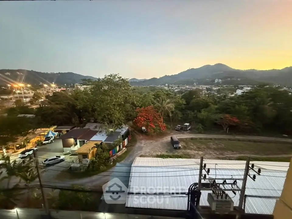 Scenic view from a property overlooking lush greenery and distant hills at sunset.