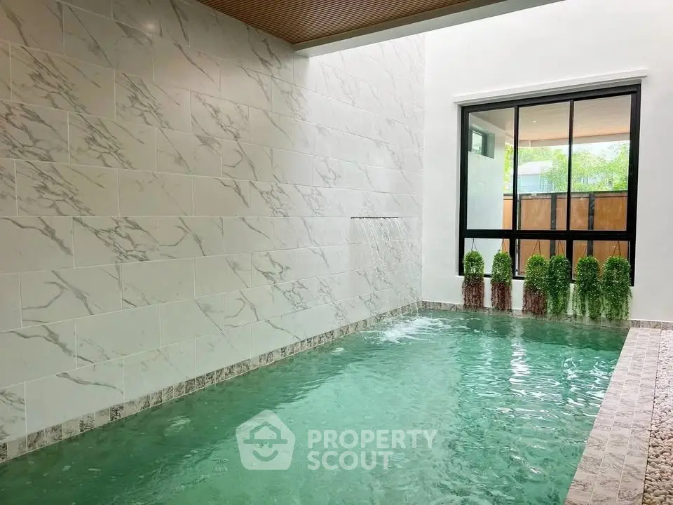 Luxurious indoor pool with elegant marble walls and large window view.
