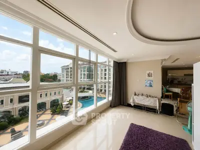 Spacious living room with large windows offering a stunning view of the pool and surrounding architecture.