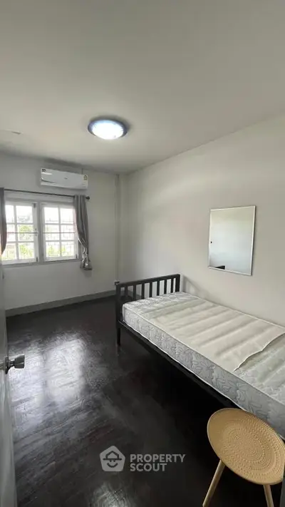 Cozy bedroom with single bed, window view, and air conditioning in a minimalist style.