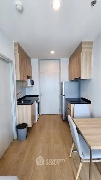 Modern kitchen with sleek appliances and wooden cabinetry in a compact layout.
