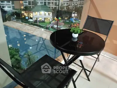 Chic balcony with modern furniture overlooking pool and garden in luxury apartment complex.