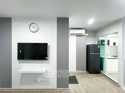 Modern living room with wall-mounted TV and sleek kitchen view