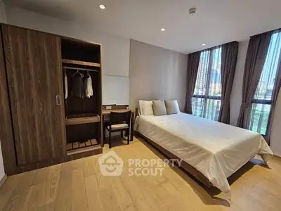 Spacious modern bedroom with wooden flooring and large windows in a luxury apartment.