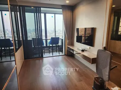 Modern living room with city view and sleek wooden flooring, featuring a wall-mounted TV and balcony access.