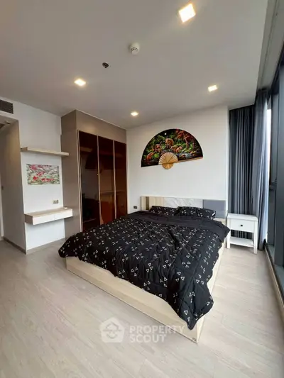 Modern bedroom with stylish decor and large windows offering natural light.