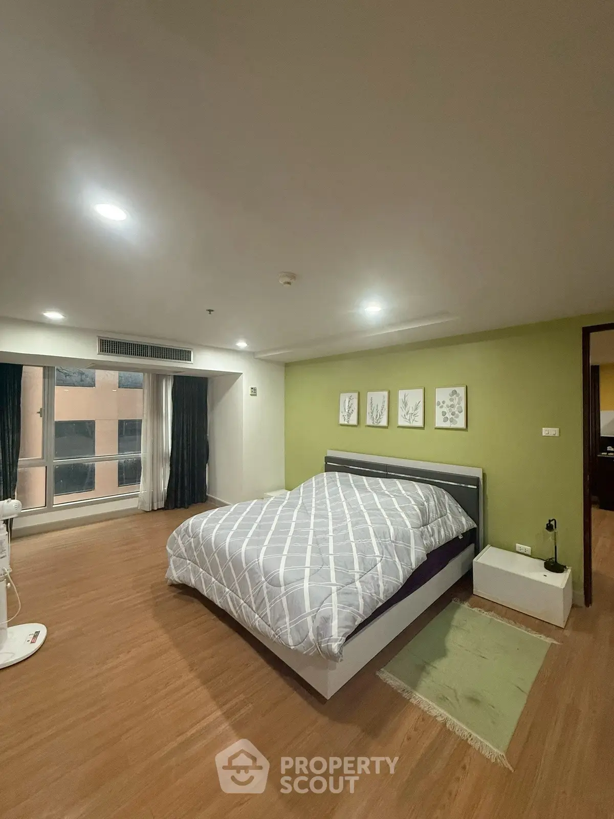 Spacious bedroom with modern decor and large window offering natural light.