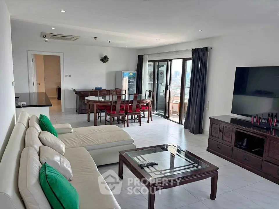 Spacious living room with modern furniture and large windows offering city views.