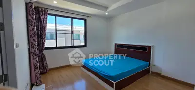 Spacious bedroom with large window and modern bed frame, offering natural light and comfort.