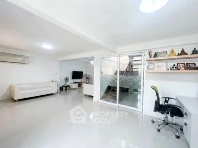 Spacious living room with modern decor and home office setup, perfect for work and relaxation.
