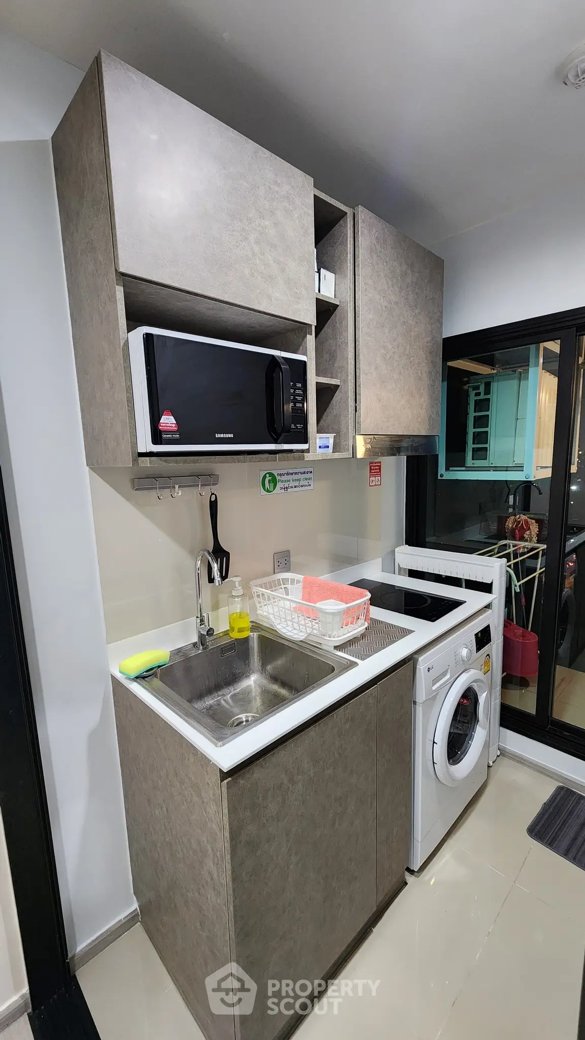 Modern kitchen with sleek cabinets, microwave, and washing machine in compact layout.