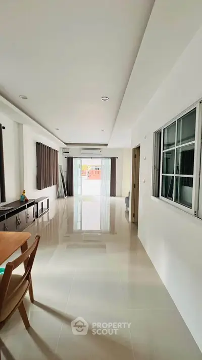 Spacious modern living room with sleek tile flooring and large windows for natural light.