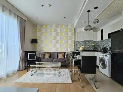 Modern open-layout living room with stylish kitchen and washing machine, featuring geometric accent wall.