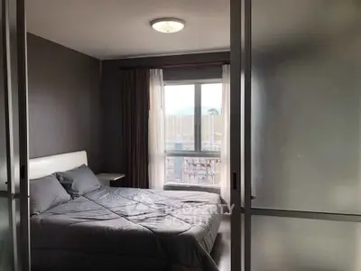 Cozy bedroom with modern decor and natural light through large window.