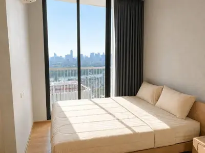 Modern bedroom with stunning city view and floor-to-ceiling windows in high-rise apartment.