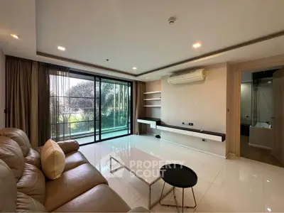Spacious modern living room with large windows and garden view, featuring sleek furniture and elegant decor.