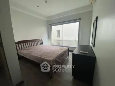 Cozy bedroom with large window and minimalist furniture in modern apartment.