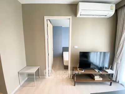 Modern living room with air conditioning and TV, leading to a cozy bedroom.