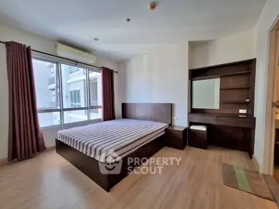 Spacious bedroom with modern furnishings and large window offering natural light.