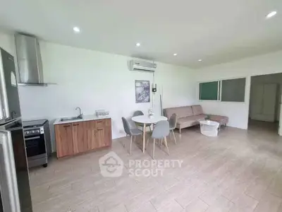 Spacious open-plan living room with modern kitchen and dining area, featuring sleek appliances and stylish decor.