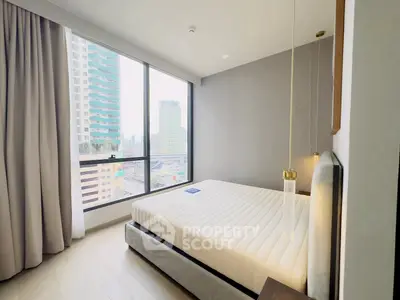 Modern bedroom with large window offering stunning city view in high-rise apartment.