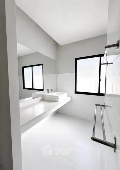 Modern minimalist bathroom with sleek white fixtures and large windows for natural light.