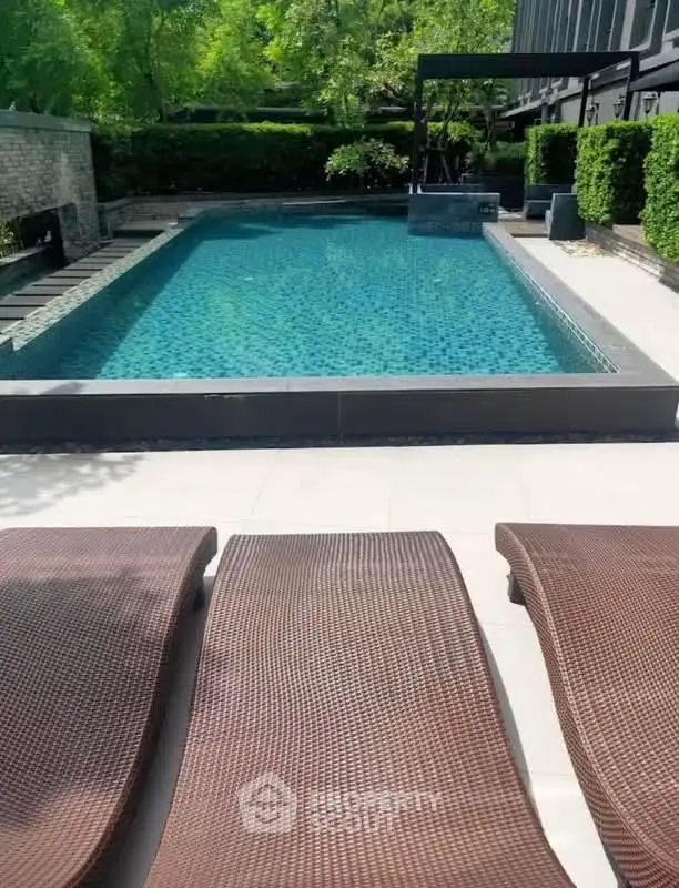 Luxurious outdoor pool area with stylish loungers and lush greenery, perfect for relaxation and leisure.