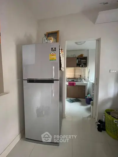Modern kitchen with sleek fridge and view into a tidy bathroom, perfect for compact living spaces.