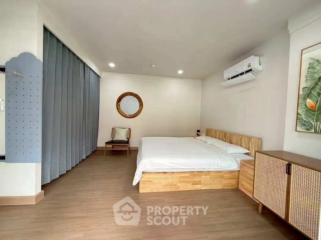 Spacious modern bedroom with wooden flooring and minimalist decor