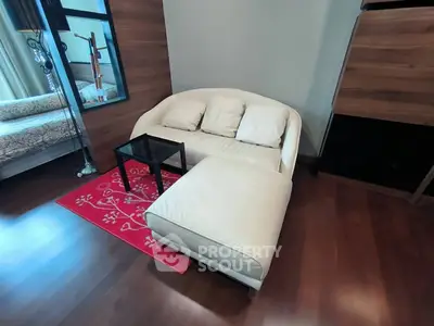 Cozy living room with modern white sofa and red rug, perfect for relaxation.
