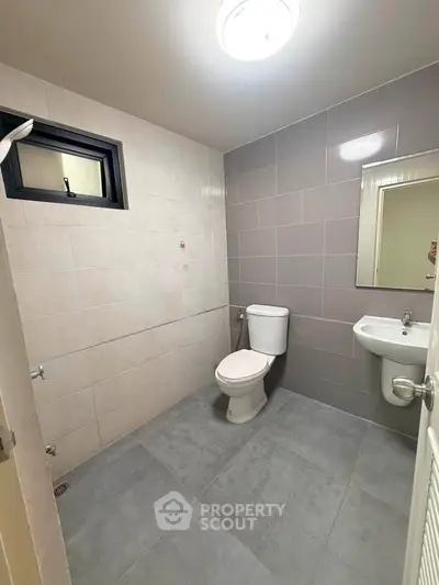 Modern bathroom with sleek gray tiles and compact fixtures in a contemporary apartment.