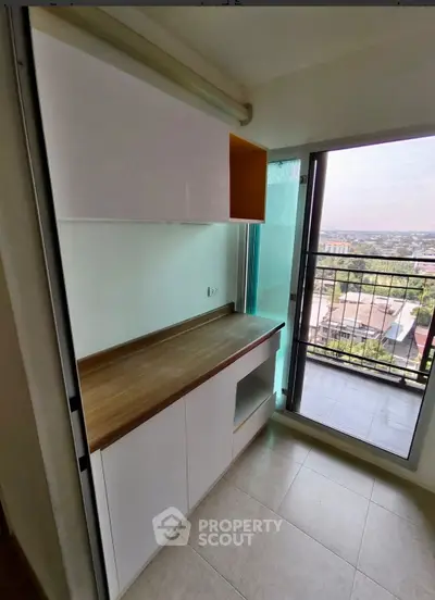 Compact kitchen with balcony view, featuring sleek cabinetry and modern design.
